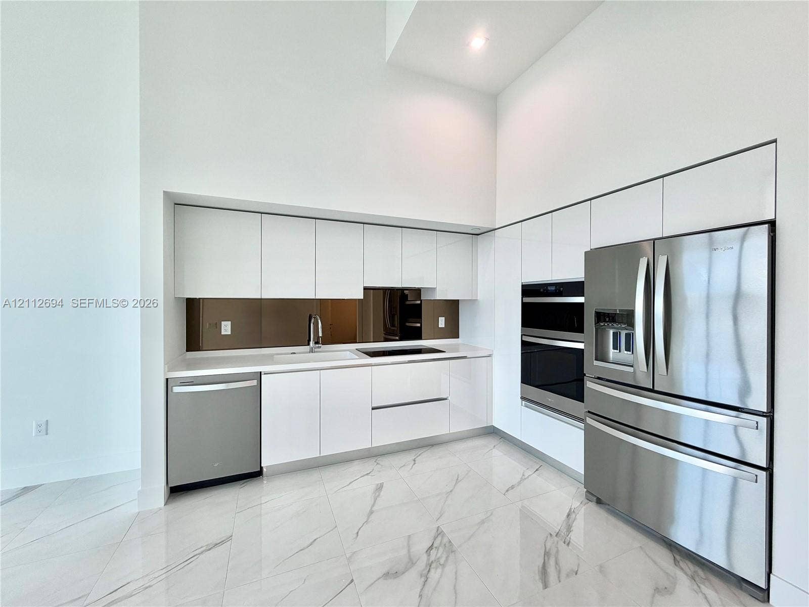 1170 E Hallandale Beach Boulevard, #503, Hallandale Beach, Hallandale Beach, FL 33009 Kitchen featuring high-gloss white cabinetry, stainless steel appliances, built-in dual wall ovens, solid-surface countertops, and large-format porcelain tile flooring