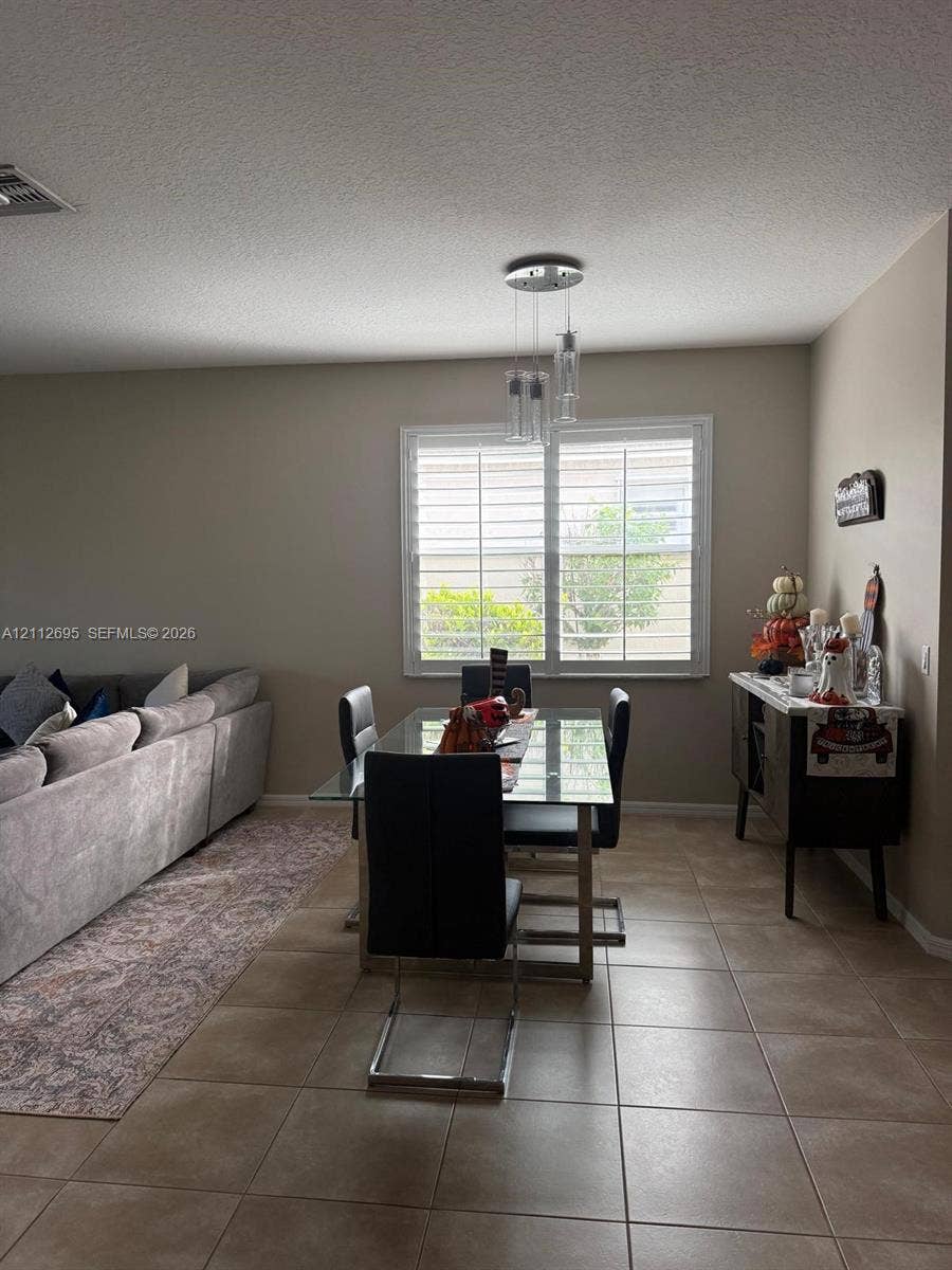 9812 SW Glenbrook Drive, Port St Lucie, FL 34987 Ceramic tile flooring, multi-pane window with plantation shutters, and a three-light glass pendant fixture