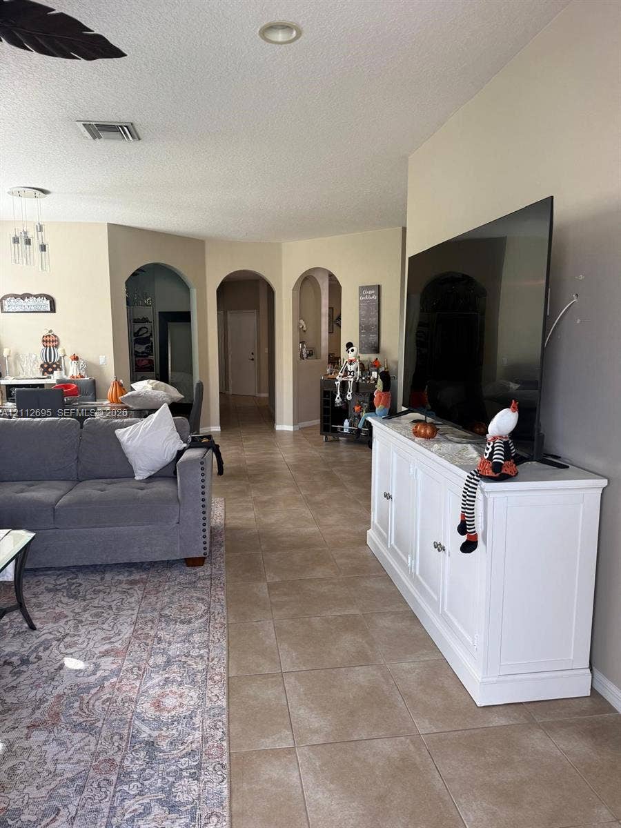 9812 SW Glenbrook Drive, Port St Lucie, FL 34987 Open-concept interior featuring large-format neutral tile flooring and distinctive arched architectural entryways