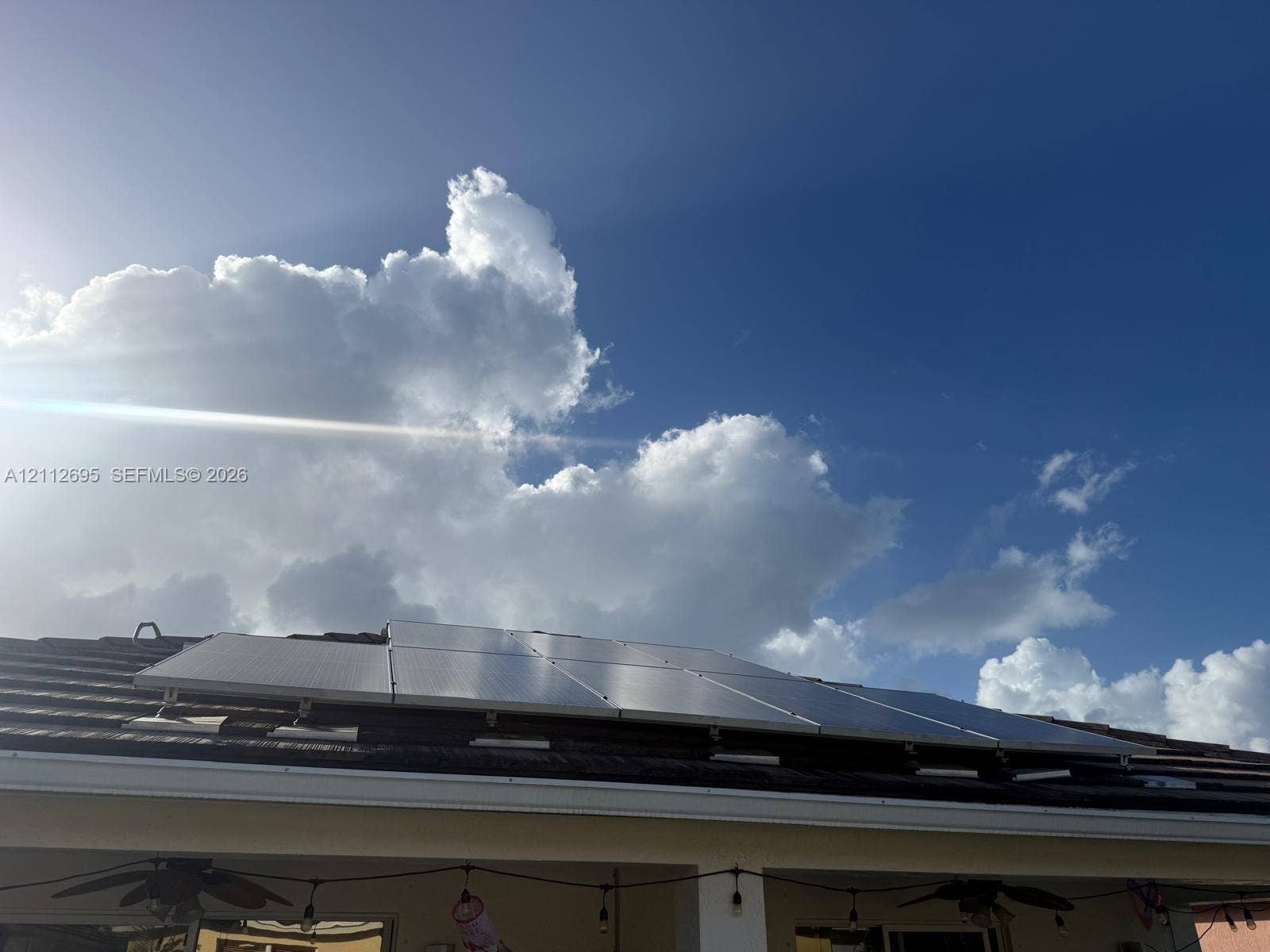 9812 SW Glenbrook Drive, Port St Lucie, FL 34987 Rooftop solar panel array mounted on a tile roof, including a covered patio area with dual ceiling fans