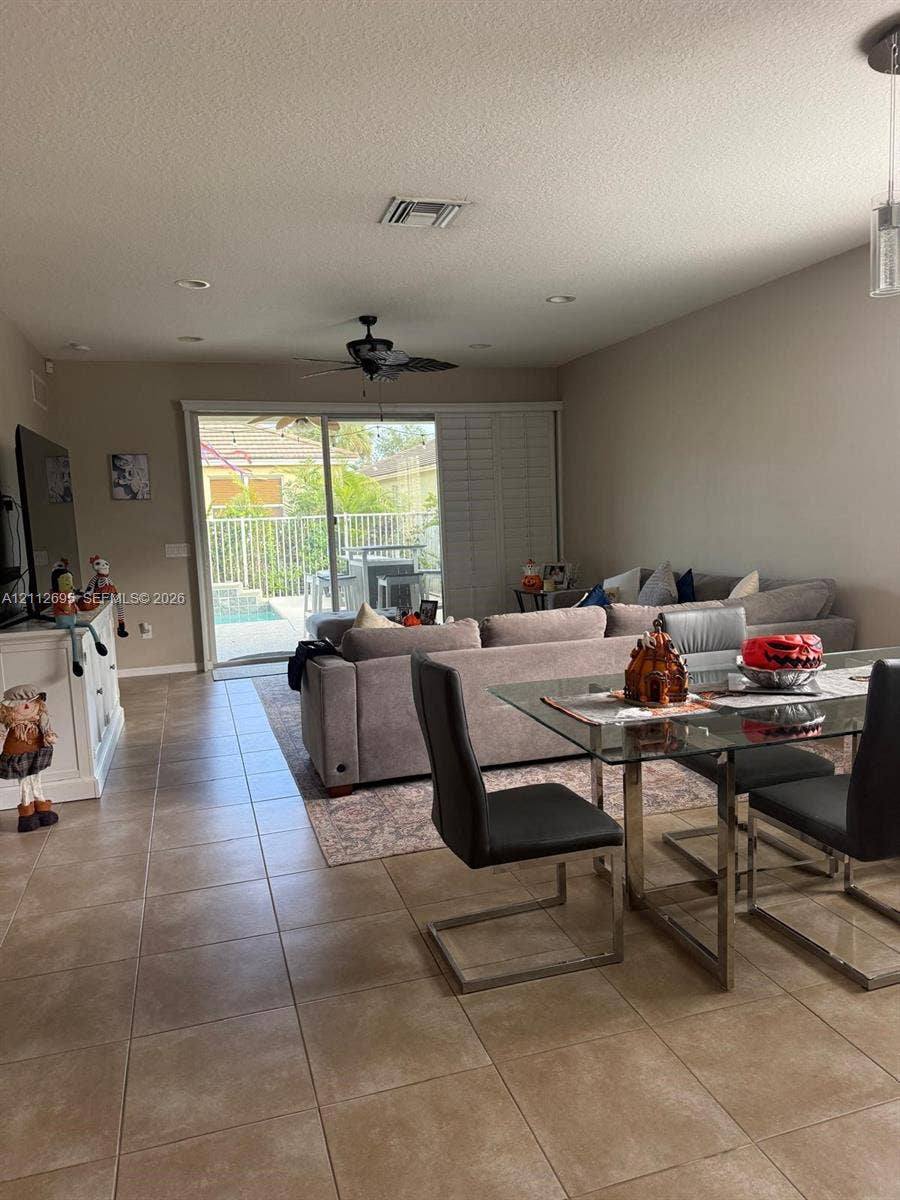9812 SW Glenbrook Drive, Port St Lucie, FL 34987 Large-format tile flooring, recessed lighting, ceiling fan, and sliding glass doors with access to a fenced outdoor area