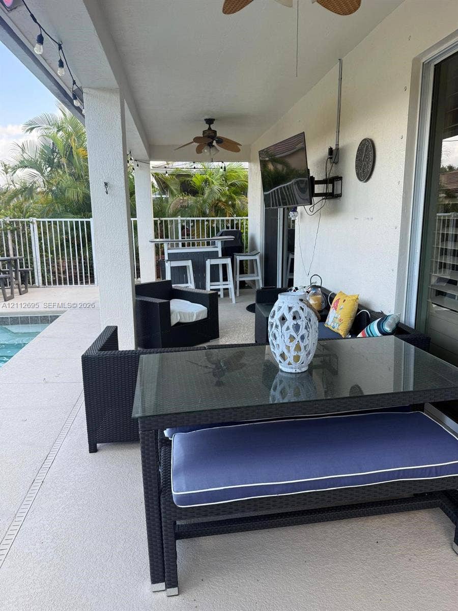 9812 SW Glenbrook Drive, Port St Lucie, FL 34987 Covered patio featuring a concrete deck, dual ceiling fans, recessed lighting, and a white metal perimeter fence
