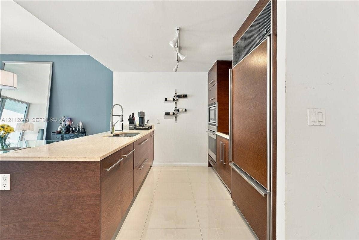 475 Brickell Avenue, #4511, Miami, FL 33131 Kitchen featuring custom wood-finish cabinetry, stone countertop, integrated refrigerator, built-in wall oven and microwave, and polished tile flooring