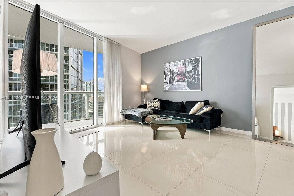 475 Brickell Avenue, #4511, Miami, FL 33131 Floor-to-ceiling glass windows, full-height sliding glass balcony door, polished tile flooring, and neutral wall tones