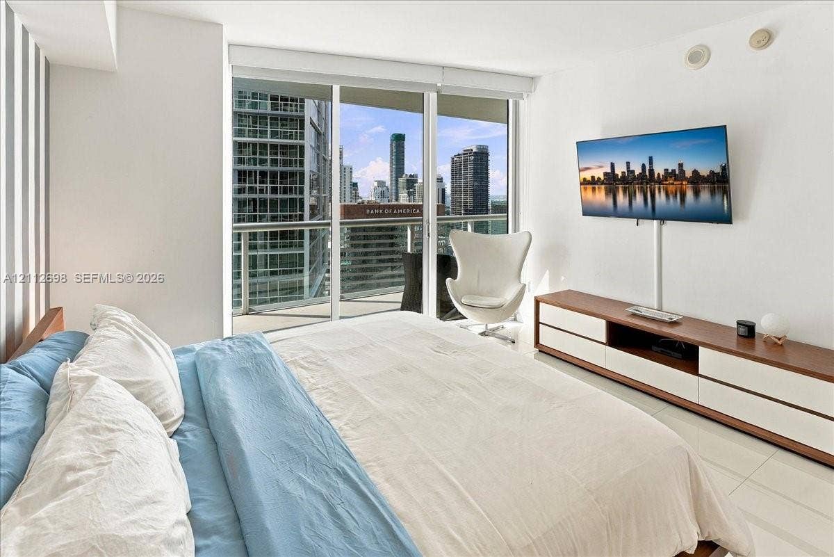 475 Brickell Avenue, #4511, Miami, FL 33131 Floor-to-ceiling sliding glass doors, white tile flooring, and a private balcony featuring a metal railing