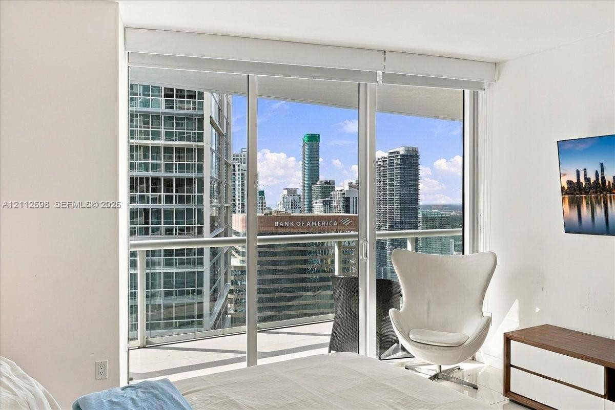475 Brickell Avenue, #4511, Miami, FL 33131 Floor-to-ceiling glass sliding doors opening to a private balcony with metal railings, offering an urban skyline panorama