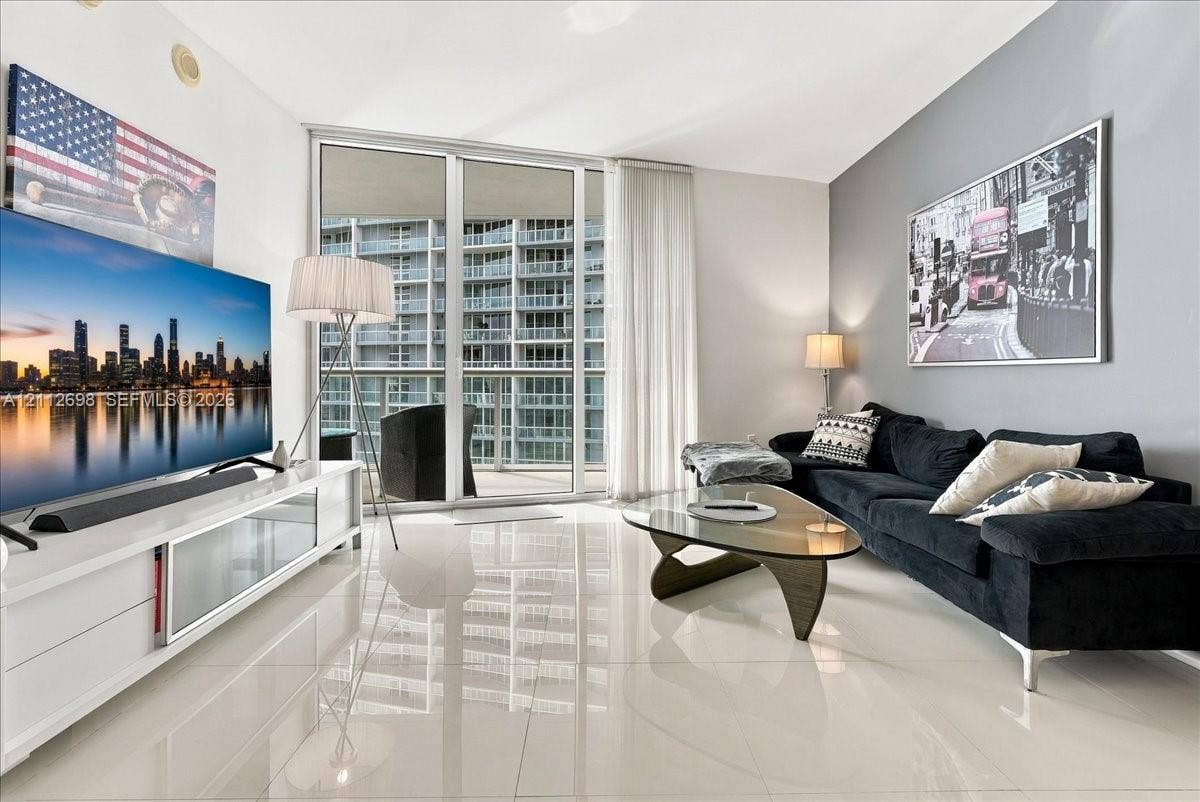 475 Brickell Avenue, #4511, Miami, FL 33131 Living space featuring large-format tile flooring, floor-to-ceiling glass sliding doors, and a decorative accent wall