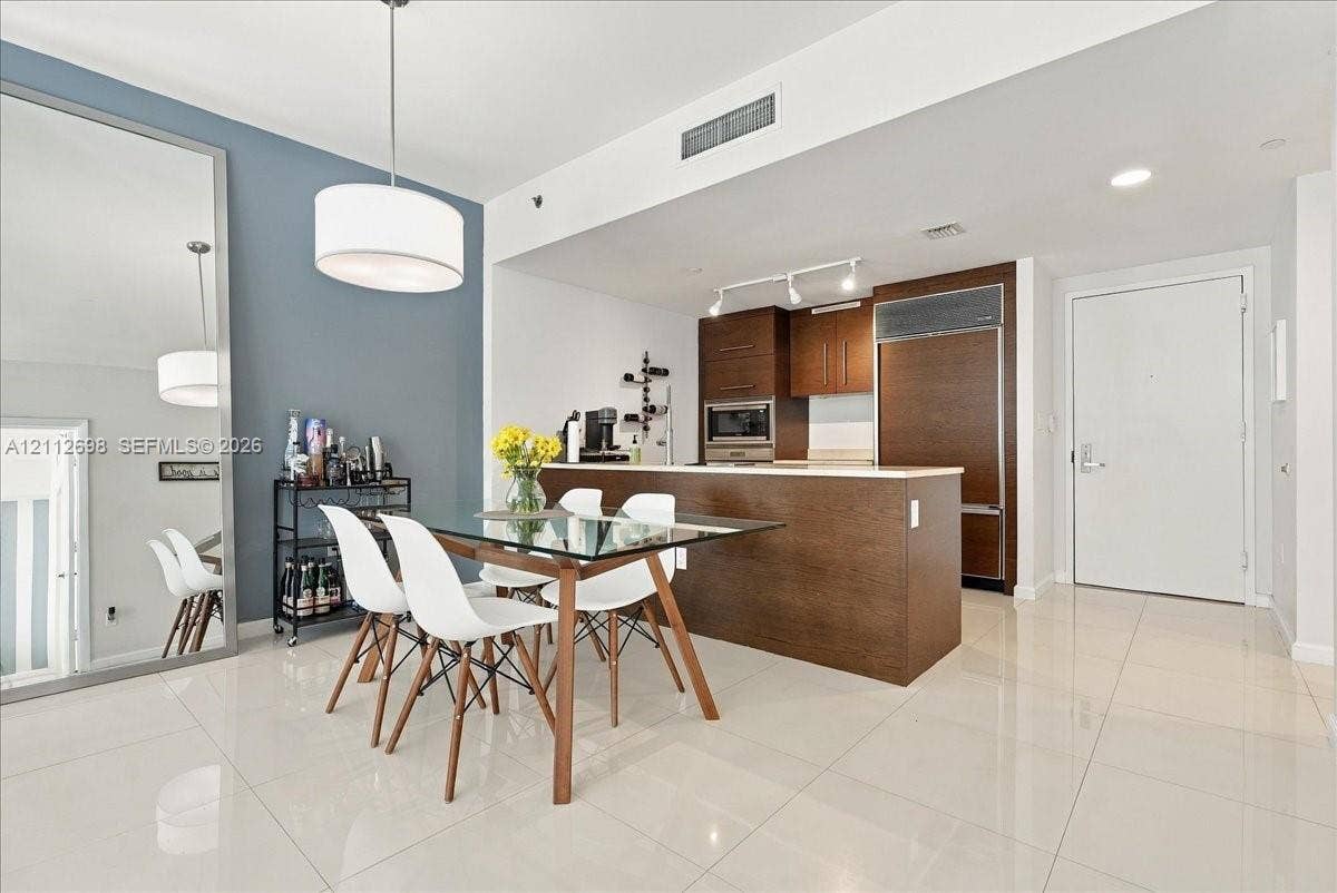 475 Brickell Avenue, #4511, Miami, FL 33131 Open-concept interior featuring large-format tile flooring, built-in cabinetry with wood-finish paneling, an integrated refrigerator, recessed track lighting, and an oversized wall mirror