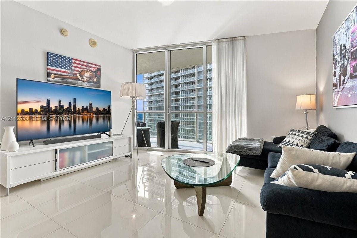 475 Brickell Avenue, #4511, Miami, FL 33131 Living area featuring high-gloss tile flooring, floor-to-ceiling glass sliding doors, and a private balcony