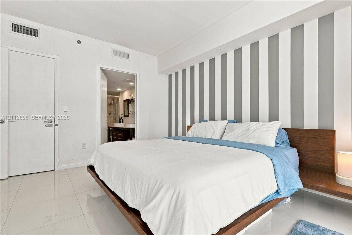 475 Brickell Avenue, #4511, Miami, FL 33131 Polished tile flooring, vertical wall accent detailing, and built-in wood-finish headboard with integrated side tables