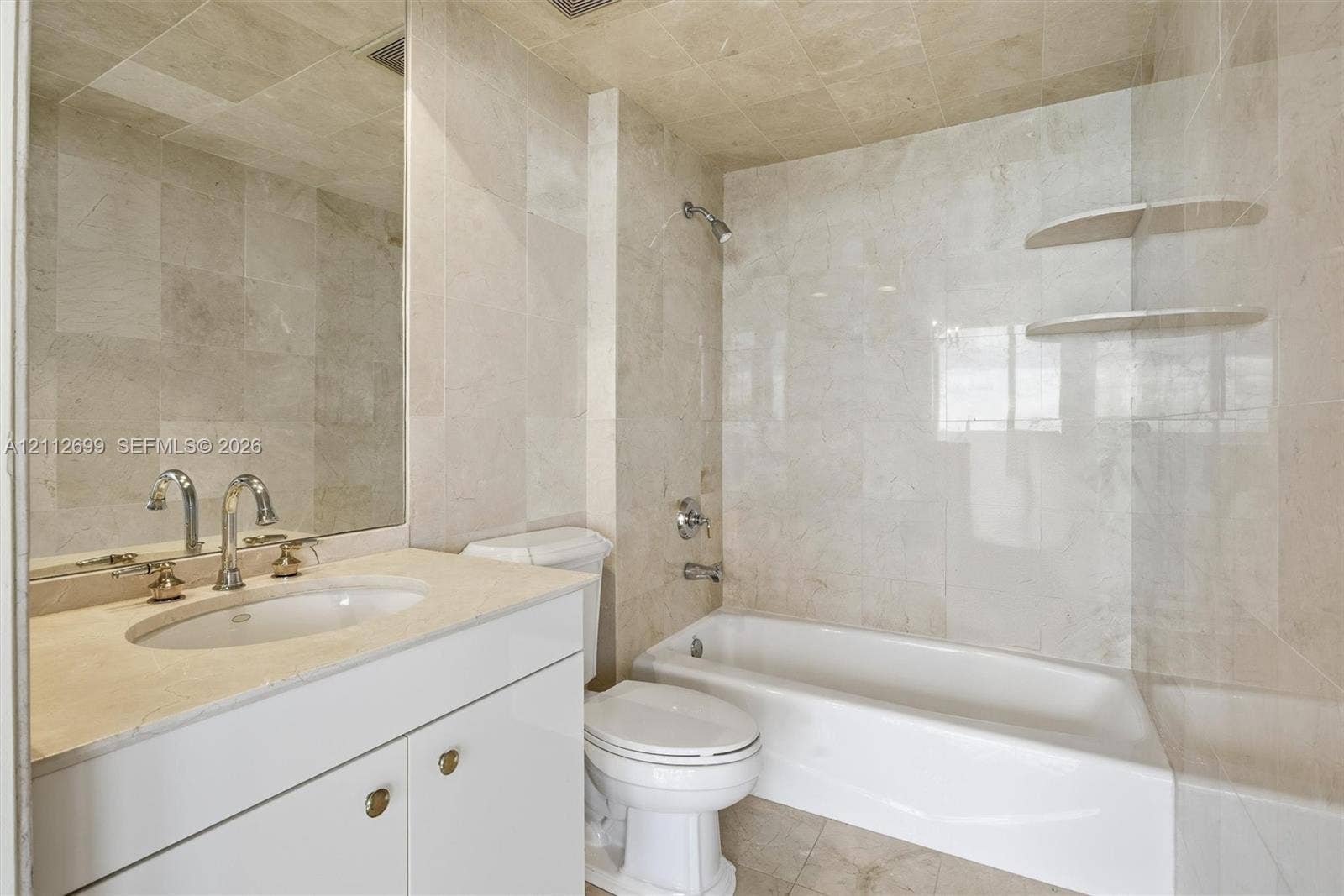 19111 Collins Avenue, #505, Sunny Isles Beach, FL 33160 Full-height stone tile wall treatments, integrated floating stone shelving, undermount sink with polished chrome hardware, custom white cabinetry with stone countertop, and recessed ceiling lighting