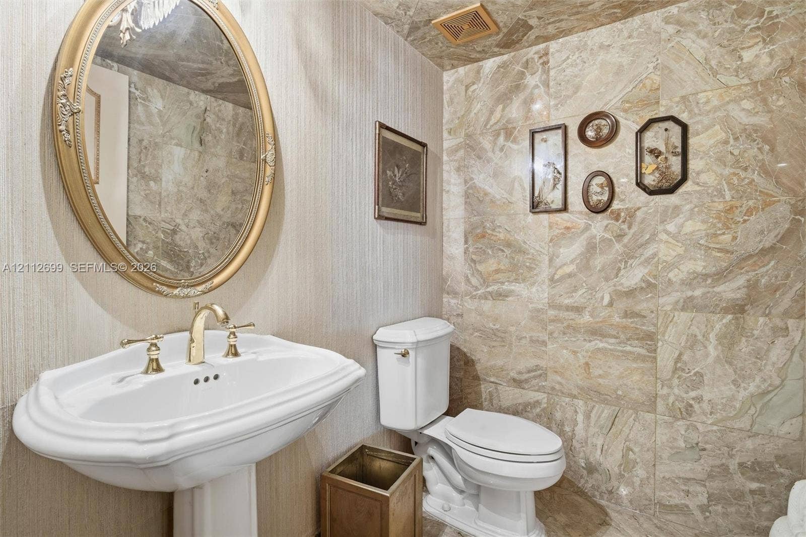 19111 Collins Avenue, #505, Sunny Isles Beach, FL 33160 Guest half a bathroom features, beautiful marble walls and ceiling, pedestal sink with brass-finish faucet, and a beautiful wall-mounted mirror