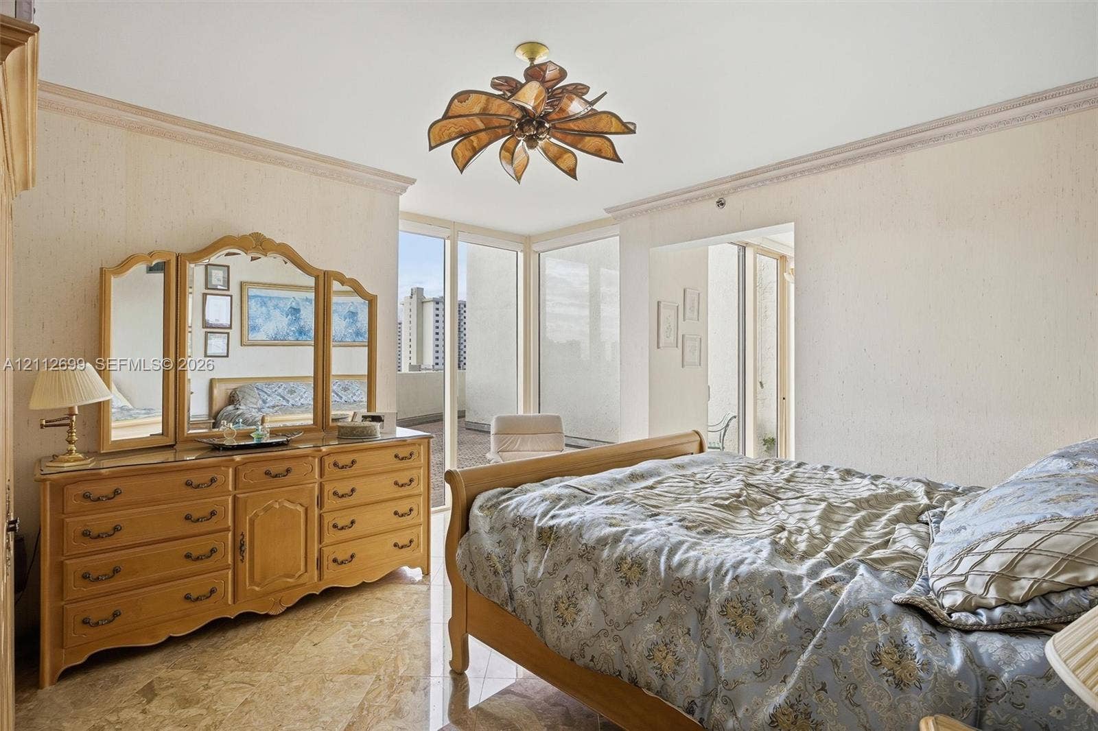 19111 Collins Avenue, #505, Sunny Isles Beach, FL 33160 Floor-to-ceiling windows, polished stone flooring, intricate crown molding, and a decorative petal-style ceiling fixture