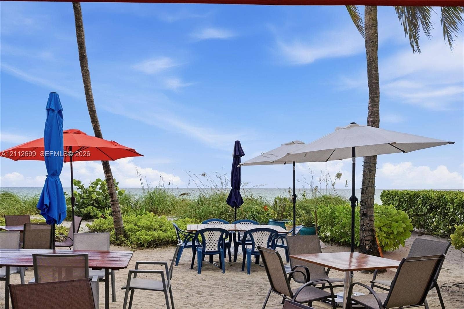 19111 Collins Avenue, #505, Sunny Isles Beach, FL 33160 Sandy beachfront patio featuring mature palm trees, native coastal vegetation, and direct access to the oceanfront