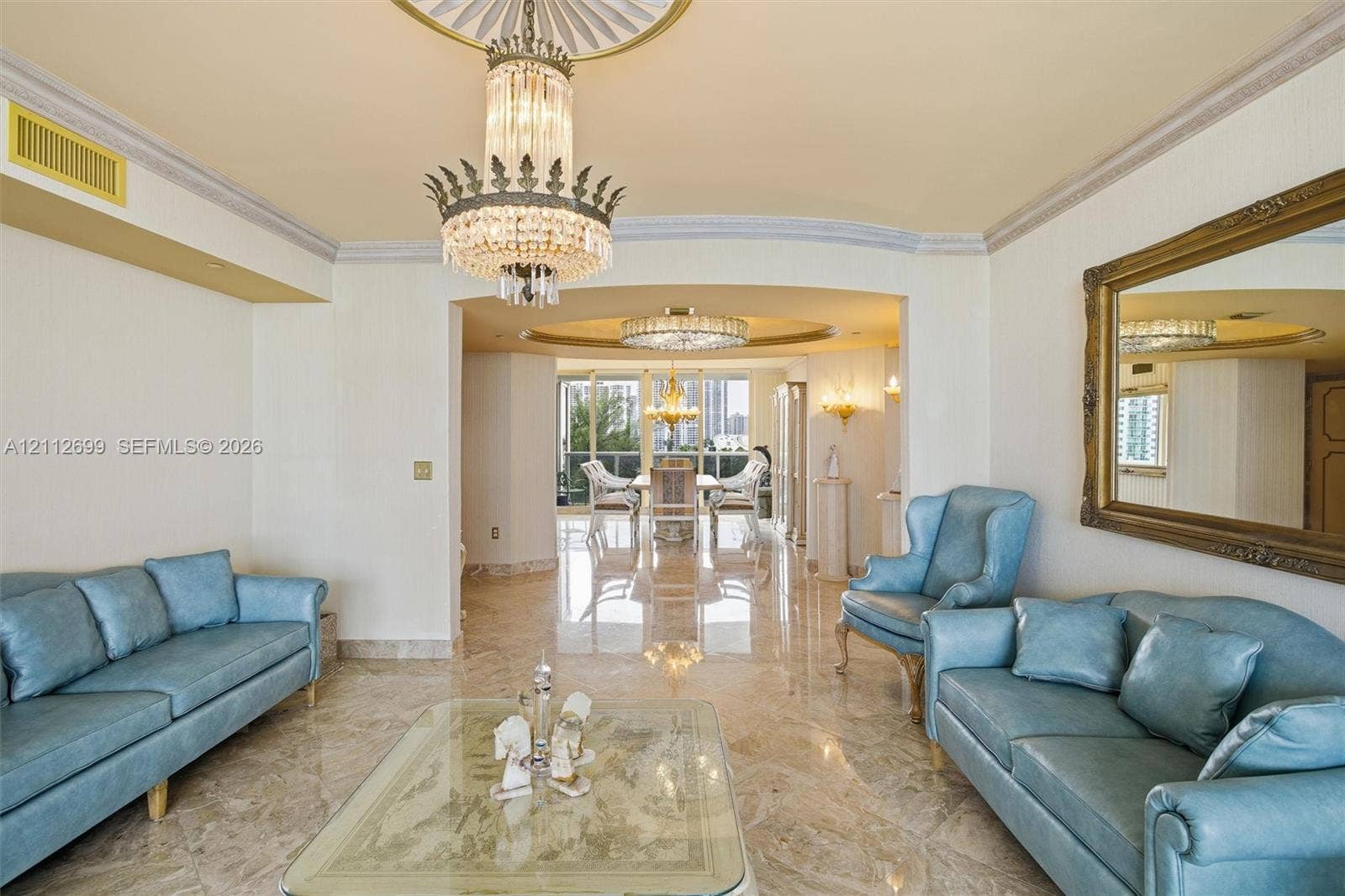 19111 Collins Avenue, #505, Sunny Isles Beach, FL 33160 Polished stone flooring, ornate crystal chandelier, recessed ceiling medallion, decorative crown molding, and expansive floor-to-ceiling windows