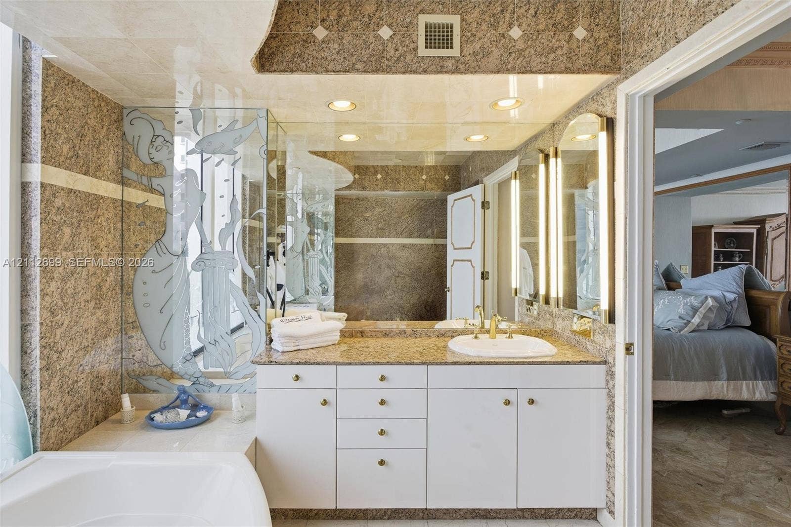 19111 Collins Avenue, #505, Sunny Isles Beach, FL 33160 Full-wall marble tilling, white vanity cabinetry with stone countertop, and integrated vertical lighting