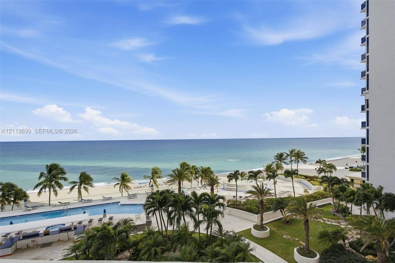 19111 Collins Avenue, #505, Sunny Isles Beach, FL 33160 Elevated perspective featuring direct oceanfront access, a sprawling swimming pool with surrounding terrace, landscaped grounds with mature palms, and expansive sand shoreline