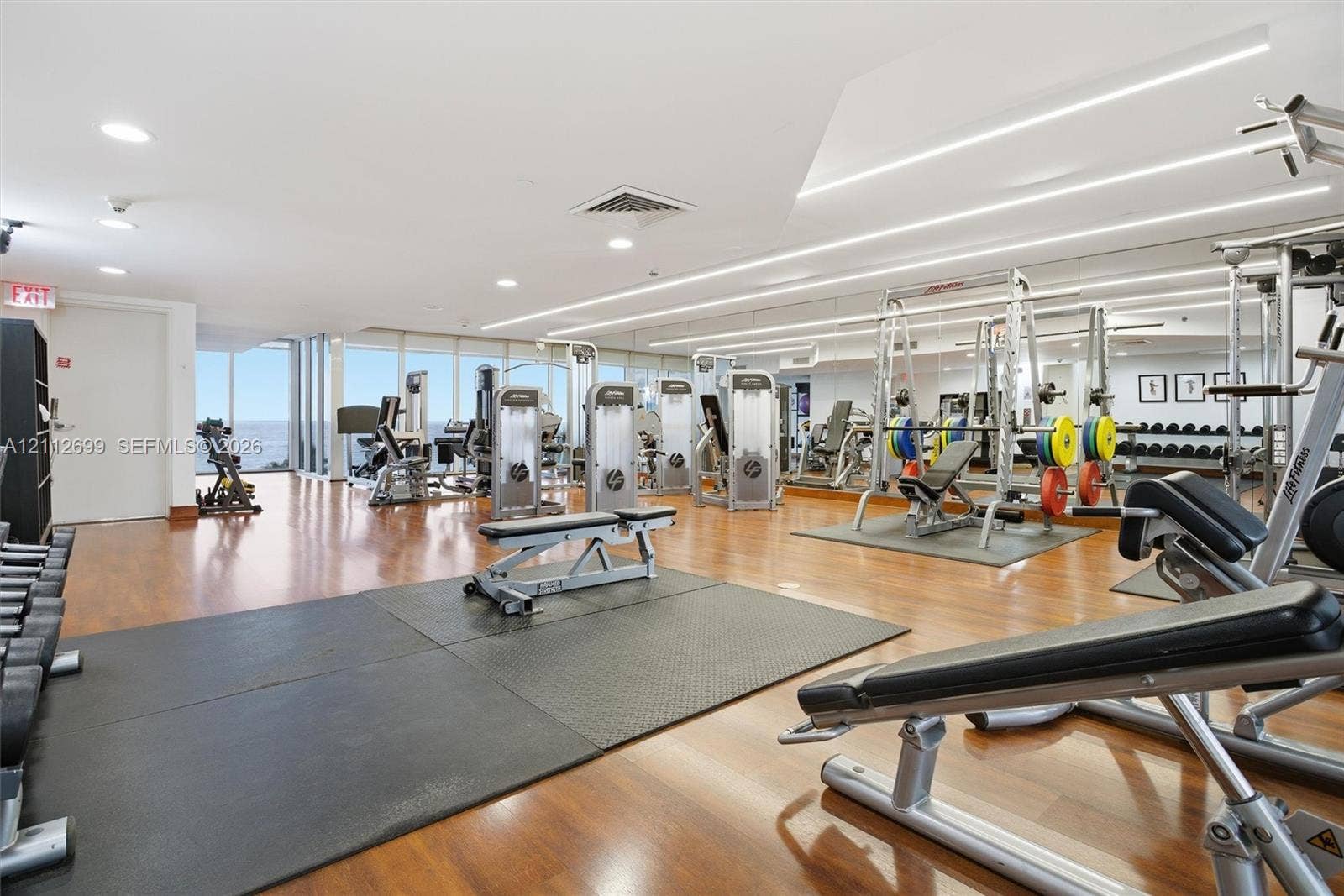19111 Collins Avenue, #505, Sunny Isles Beach, FL 33160 Fitness center featuring wood-finish flooring, full-wall mirrors, recessed lighting, and expansive floor-to-ceiling windows