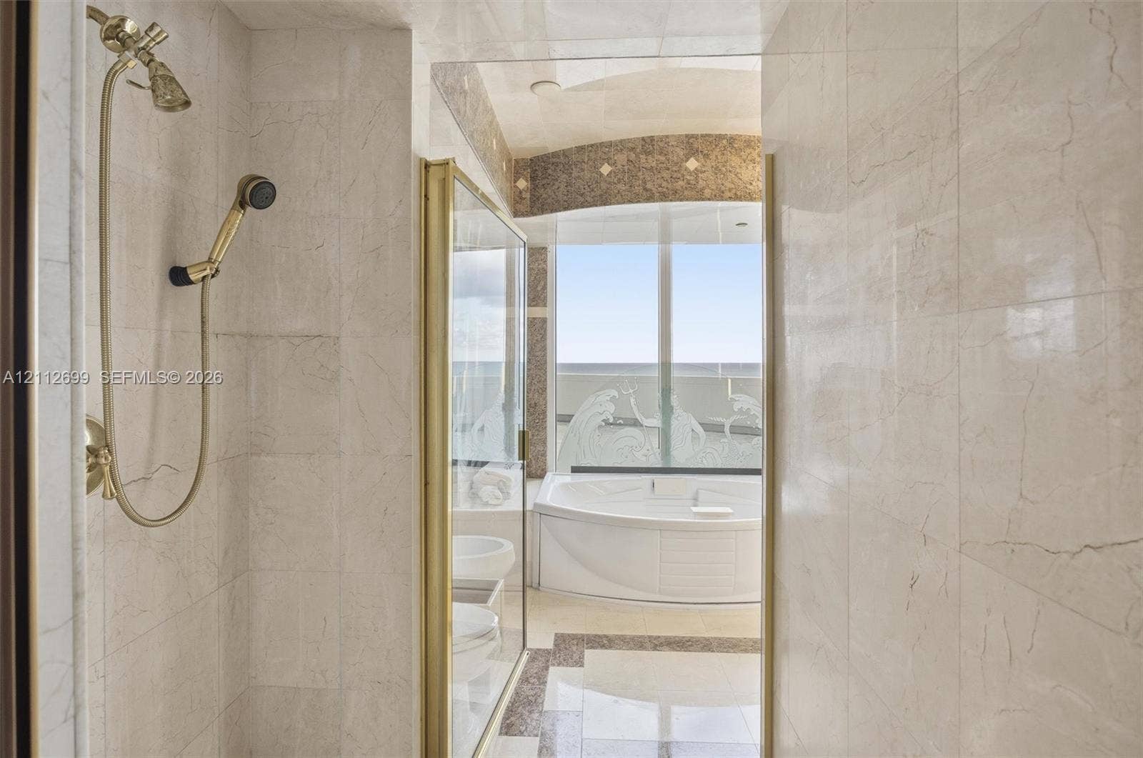 19111 Collins Avenue, #505, Sunny Isles Beach, FL 33160 Stone-tiled shower connects two bathrooms in the primary bedroom.