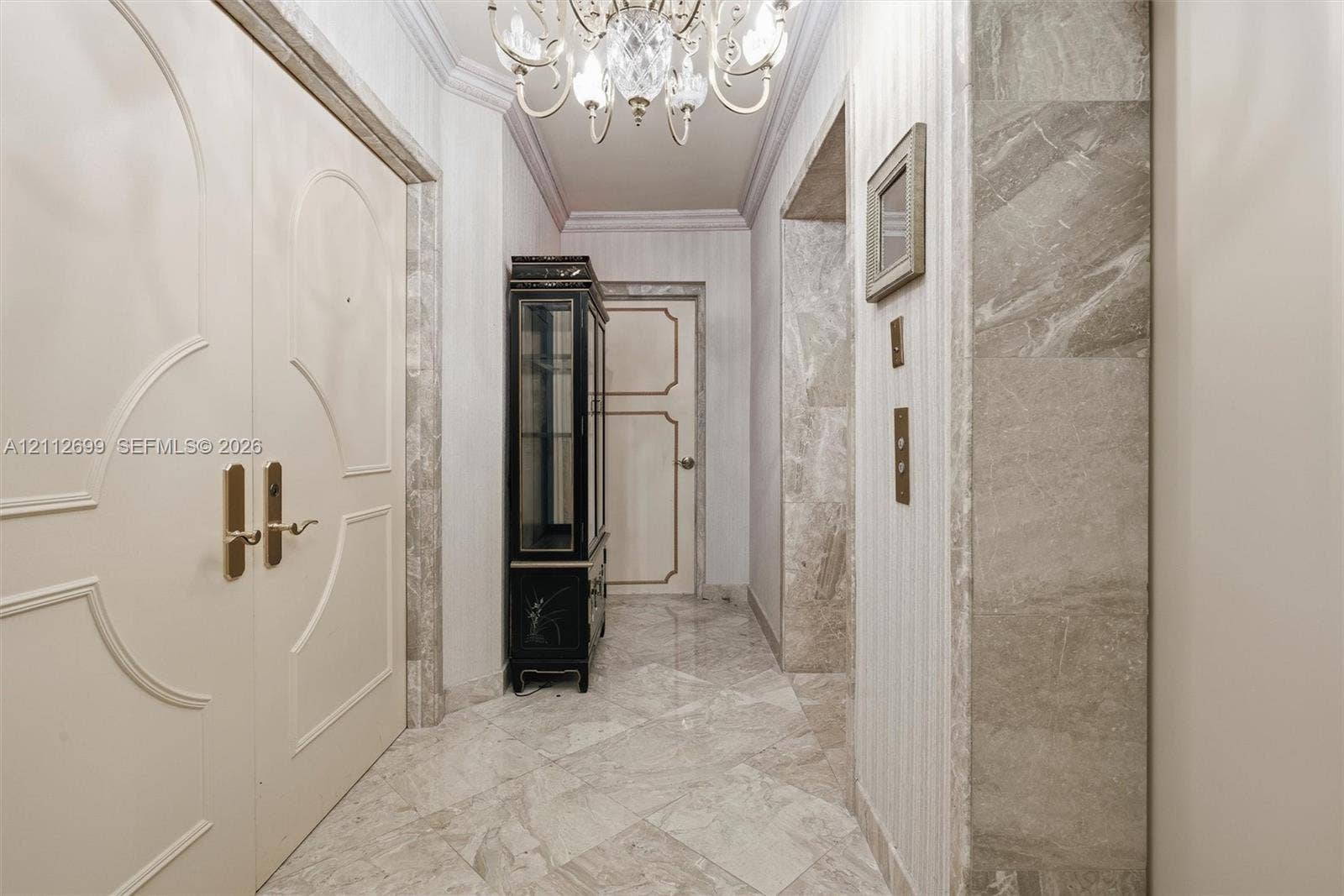 19111 Collins Avenue, #505, Sunny Isles Beach, FL 33160 Entryway from a private elevator lobby. Featuring double doors with decorative millwork, stone tile flooring, crown molding, and stone wall accents