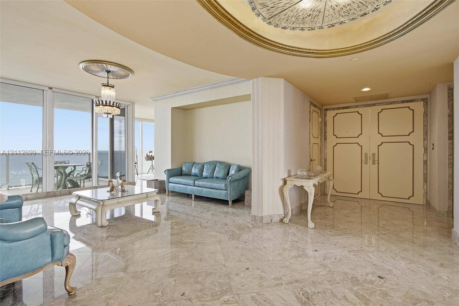19111 Collins Avenue, #505, Sunny Isles Beach, FL 33160 Polished stone flooring, recessed ceiling with gold-leaf detailing, dual-panel entry door with gold trim, crystal chandelier, and wall-to-wall glass sliding doors