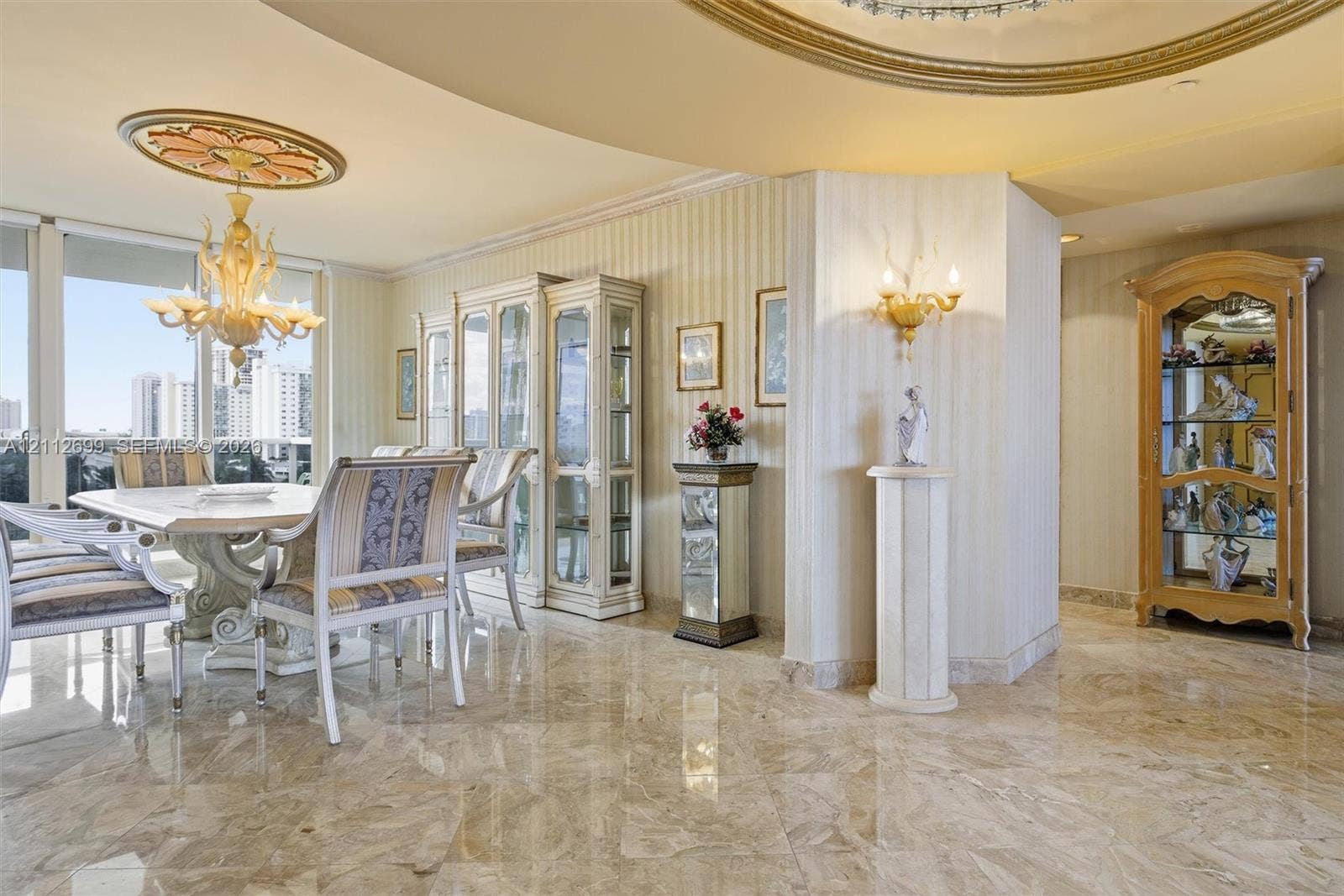 19111 Collins Avenue, #505, Sunny Isles Beach, FL 33160 Polished stone flooring, custom architectural ceiling molding, decorative ceiling medallion, built-in cabinetry, and wall-mounted sconces