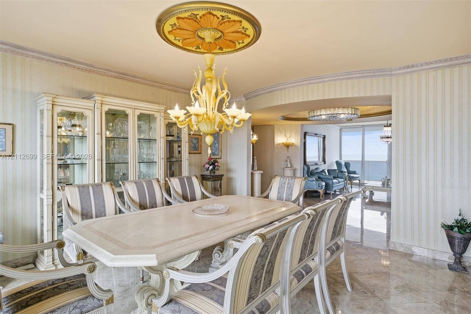 19111 Collins Avenue, #505, Sunny Isles Beach, FL 33160 Formal dining area featuring stone flooring, integrated built-in cabinetry, an ornate decorative ceiling medallion, and a multi-arm chandelier
