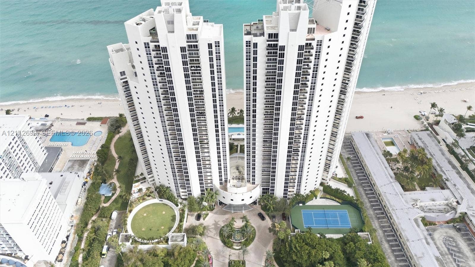 19111 Collins Avenue, #505, Sunny Isles Beach, FL 33160 High-rise residential towers featuring direct oceanfront access, a private tennis court, an outdoor swimming pool, and landscaped grounds