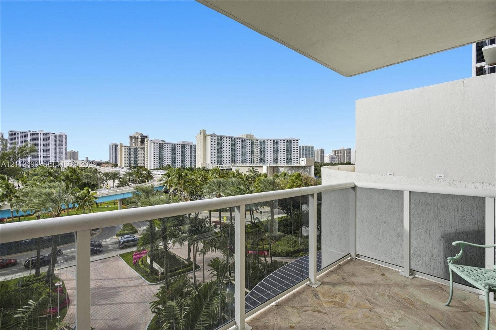 19111 Collins Avenue, #505, Sunny Isles Beach, FL 33160 Covered balcony featuring stone flooring and a glass-paneled railing