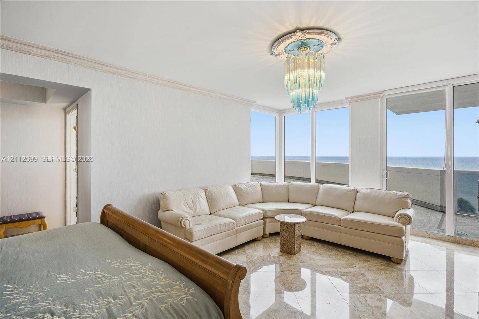 19111 Collins Avenue, #505, Sunny Isles Beach, FL 33160 Floor-to-ceiling windows, polished stone flooring, intricate crown molding, and decorative ceiling medallion with a tiered glass chandelier