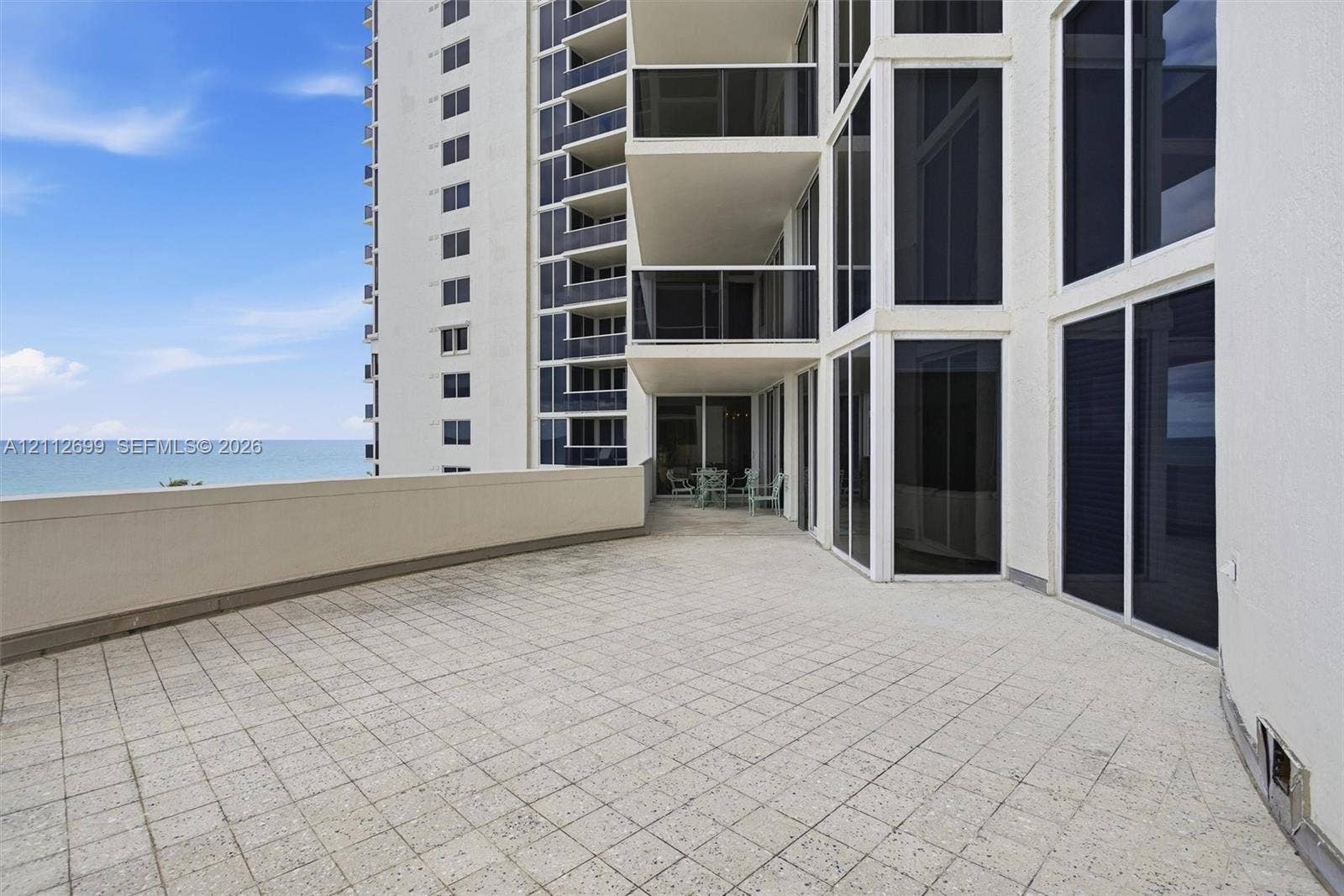 19111 Collins Avenue, #505, Sunny Isles Beach, FL 33160 Expansive tiled terrace featuring a solid-surface perimeter wall, floor-to-ceiling glass windows, and sliding glass doors