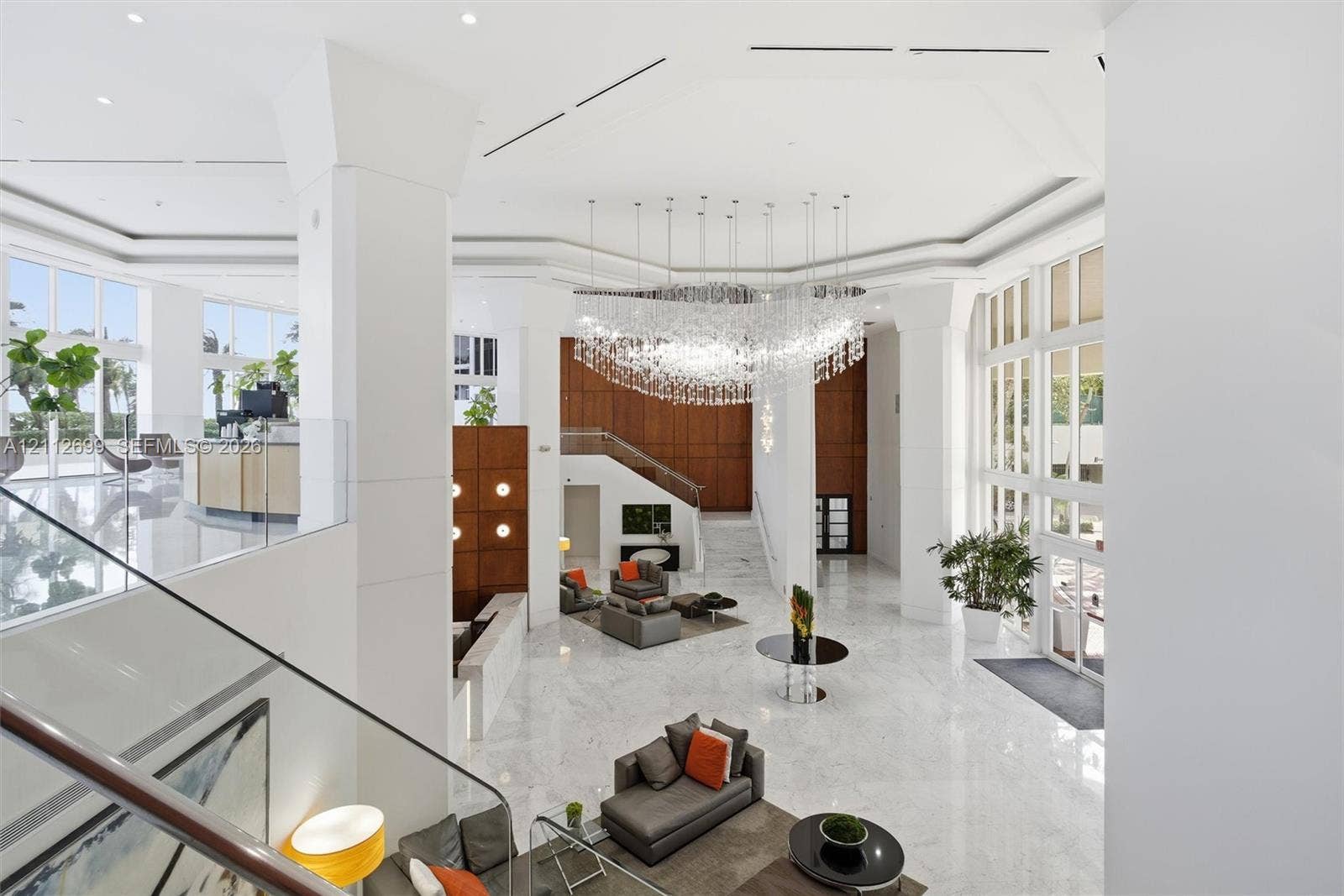 19111 Collins Avenue, #505, Sunny Isles Beach, FL 33160 Grand atrium featuring high ceilings, stone flooring, a multi-tiered crystal chandelier, expansive floor-to-ceiling windows, and wood-paneled walls
