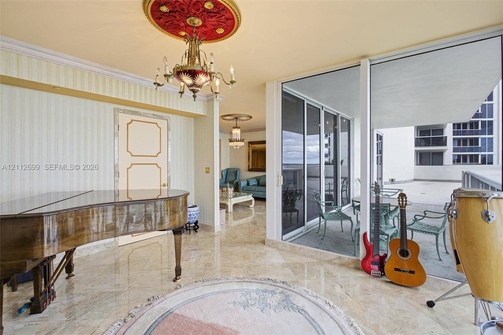 19111 Collins Avenue, #505, Sunny Isles Beach, FL 33160 Polished stone flooring, intricate ceiling medallions with ornate light fixtures, and wall-to-wall sliding glass doors opening to an expansive balcony