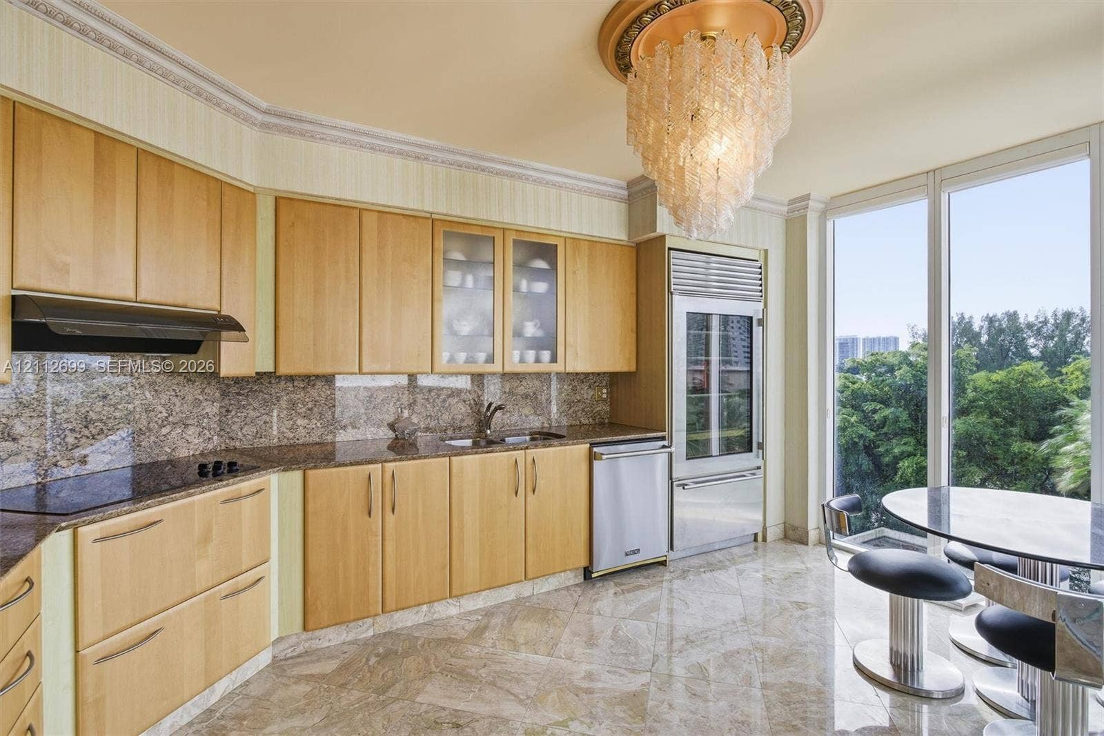 19111 Collins Avenue, #505, Sunny Isles Beach, FL 33160 Kitchen featuring light wood cabinetry, stone countertops, stone flooring, built-in stainless steel appliances, and a tiered glass chandelier