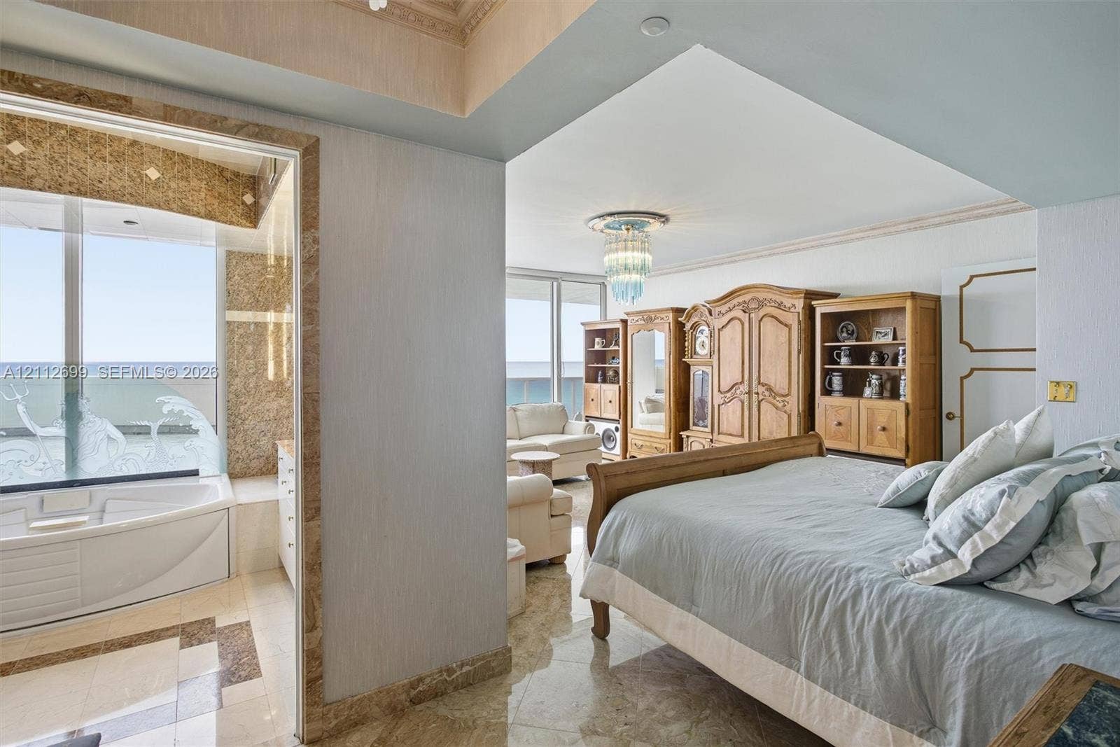 19111 Collins Avenue, #505, Sunny Isles Beach, FL 33160 Polished stone flooring, crown molding, built-in recessed lighting, decorative crystal-style chandelier, and jetted corner soaking tub featuring stone tile surround