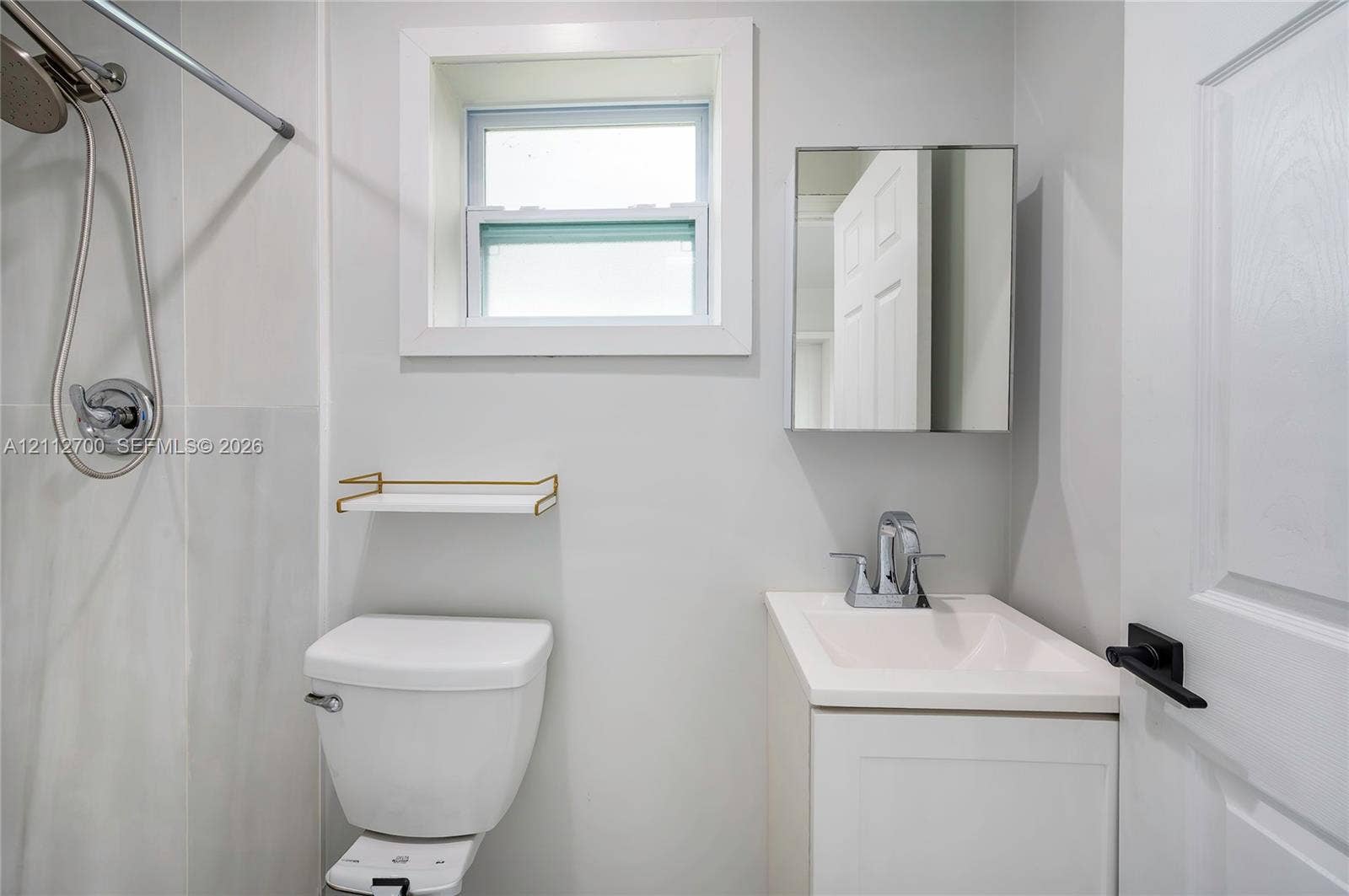 Bathroom featuring a white pedestal vanity, chrome fixtures, a recessed mirror cabinet, and a single-hung window with crisp trim