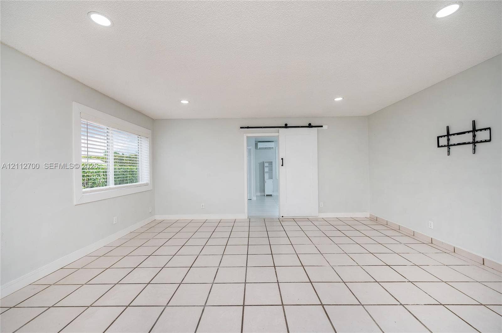 Interior space featuring ceramic tile flooring, recessed lighting, a sliding barn-style door, and a dual-pane window with white trim