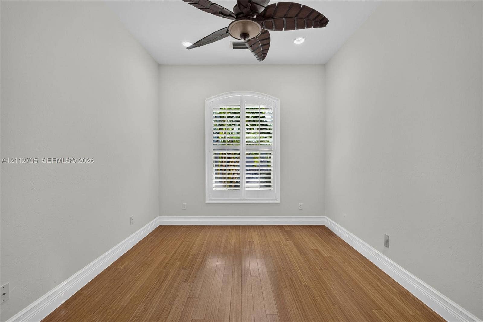 15600 Catalpa Cove Drive, Naples, FL 33908 Room featuring wood-finish flooring, recessed lighting, and a multi-blade ceiling fan, accented by an arched window with plantation shutters