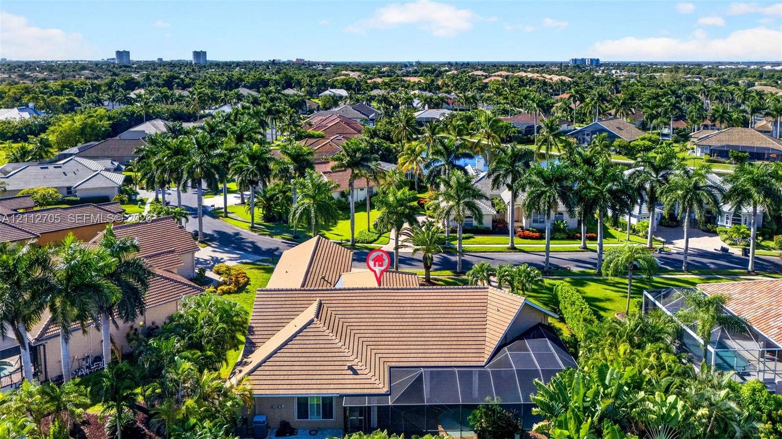 15600 Catalpa Cove Drive, Naples, FL 33908 Aerial perspective featuring a tile roof, screened-in rear enclosure, and surrounding mature landscaping within a residential community