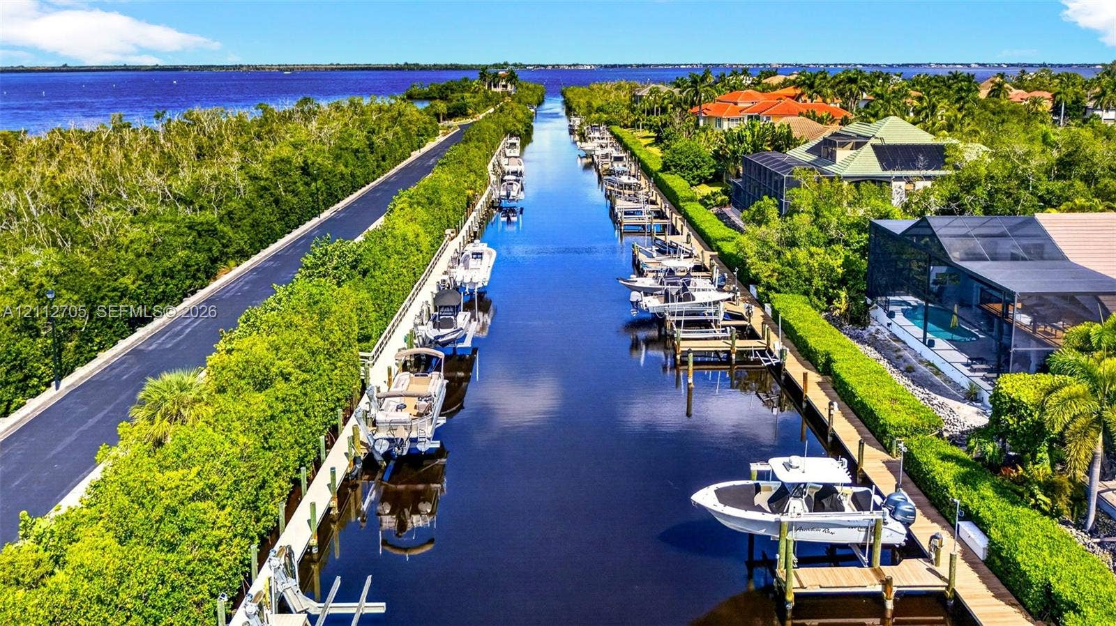 15600 Catalpa Cove Drive, Naples, FL 33908 Waterfront property featuring a private boat dock, deep-water canal access, screen-enclosed pool, and coastal landscape