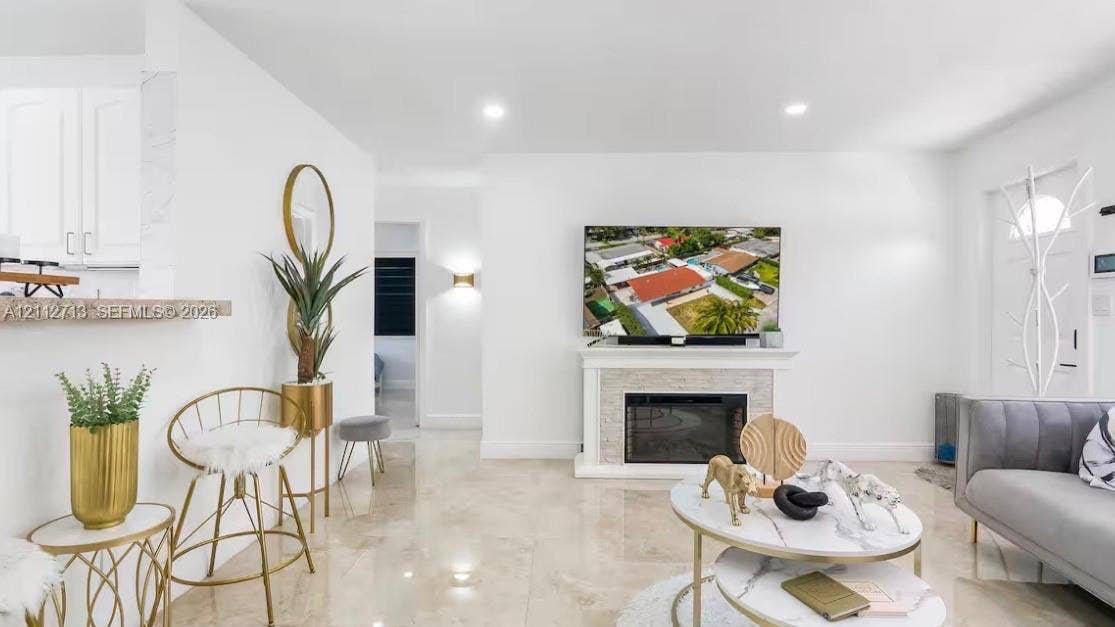 Living area featuring stone-finish flooring, a built-in fireplace with a textured surround, recessed lighting, and a breakfast bar with stone-finish counters