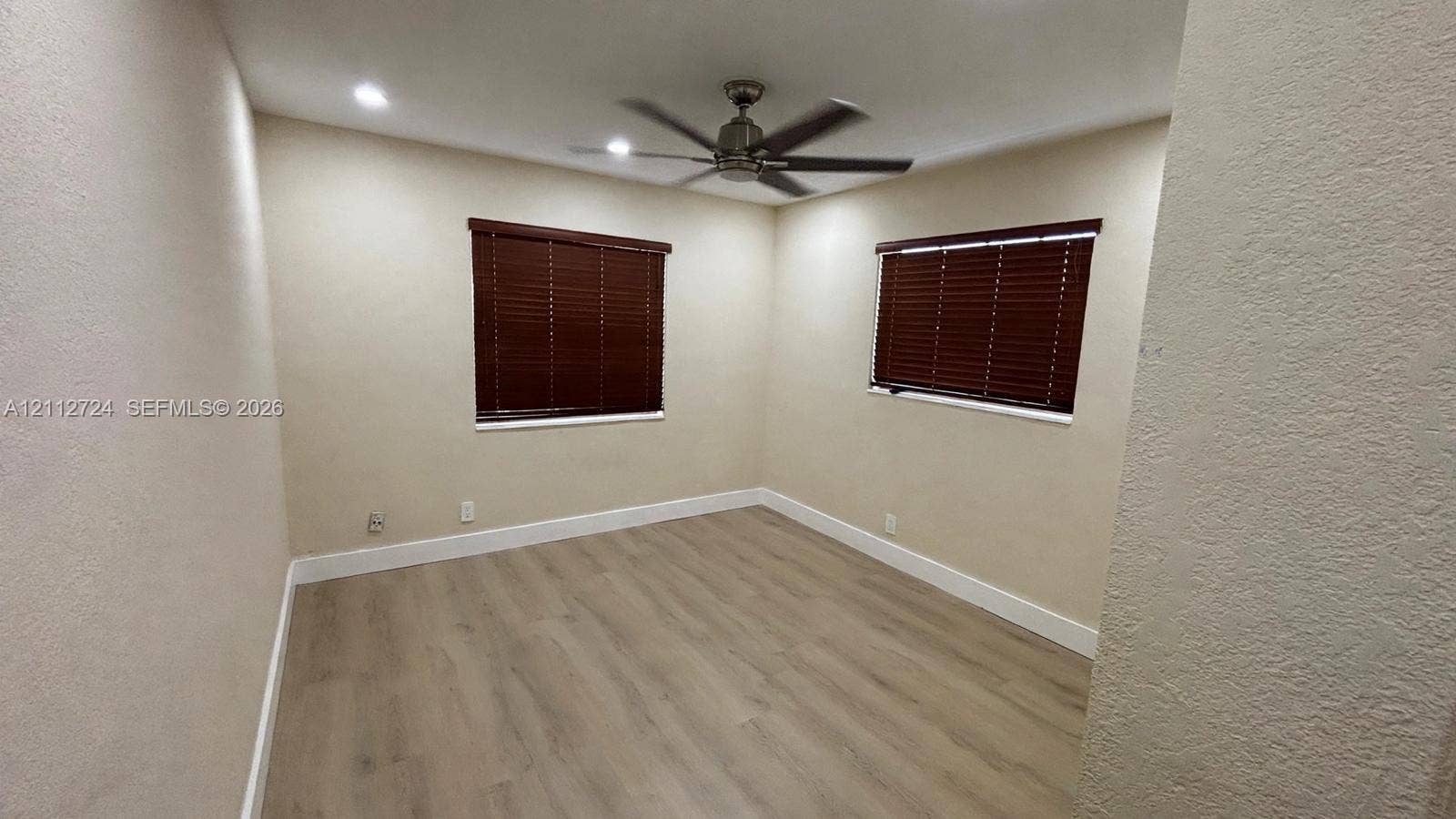 Interior space featuring wood-finish flooring, recessed lighting, a ceiling fan, and windows equipped with fitted blinds