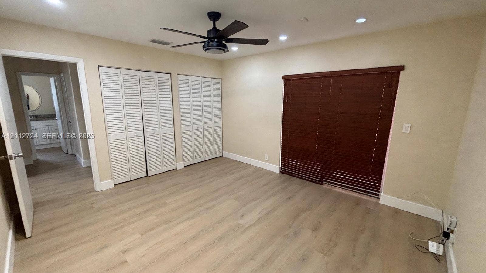 Wood-finish flooring, recessed lighting, ceiling fan with integrated light, double louvered-door closets, and floor-to-ceiling wood blinds