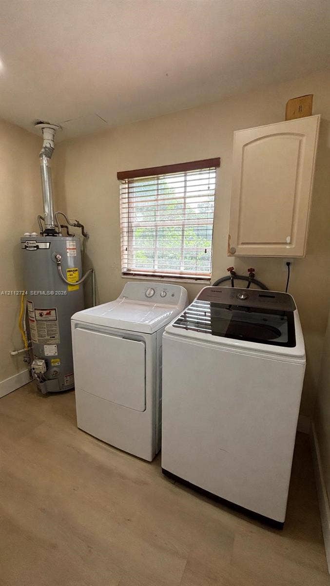 Utility area featuring wood-finish flooring, a wall-mounted cabinet, and an integrated window with horizontal blinds