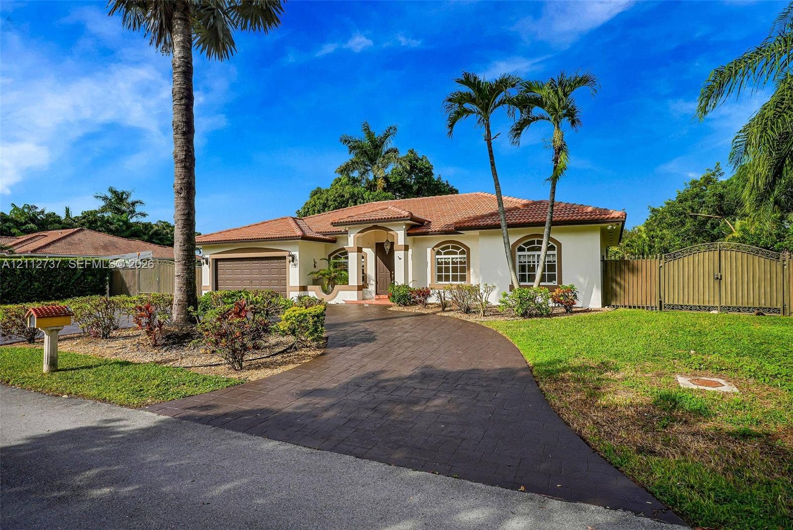 27902 SW 159th Court, Homestead, FL 33031 Single-story exterior featuring a clay tile roof, arched window detailing, paved driveway, and mature landscaping