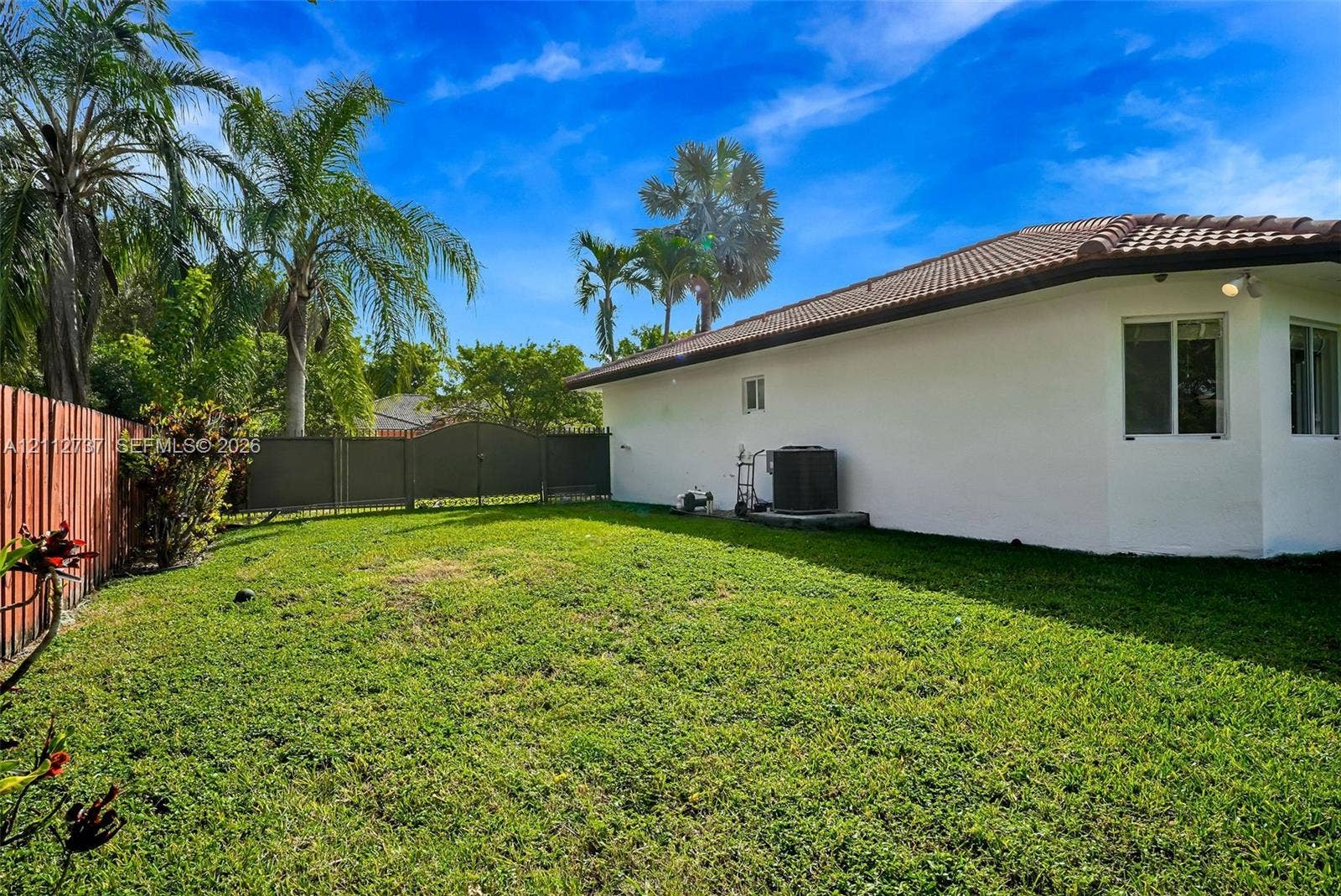 27902 SW 159th Court, Homestead, FL 33031 Backyard featuring a manicured lawn, perimeter fencing, and mature palm trees
