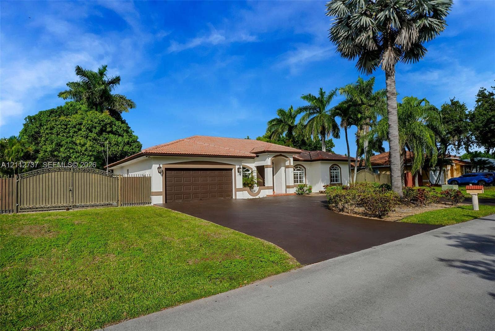 27902 SW 159th Court, Homestead, FL 33031 Single-story exterior featuring a clay tile roof, arched entryway, paved driveway, and decorative privacy fencing