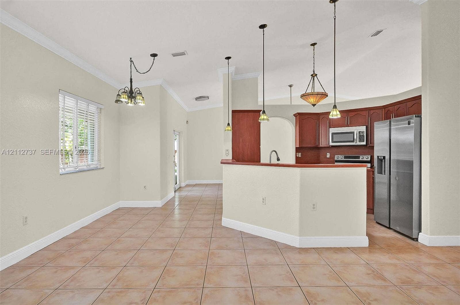 27902 SW 159th Court, Homestead, FL 33031 Kitchen featuring wood cabinetry, stainless steel appliances, tile flooring, vaulted ceilings, and multi-pendant lighting
