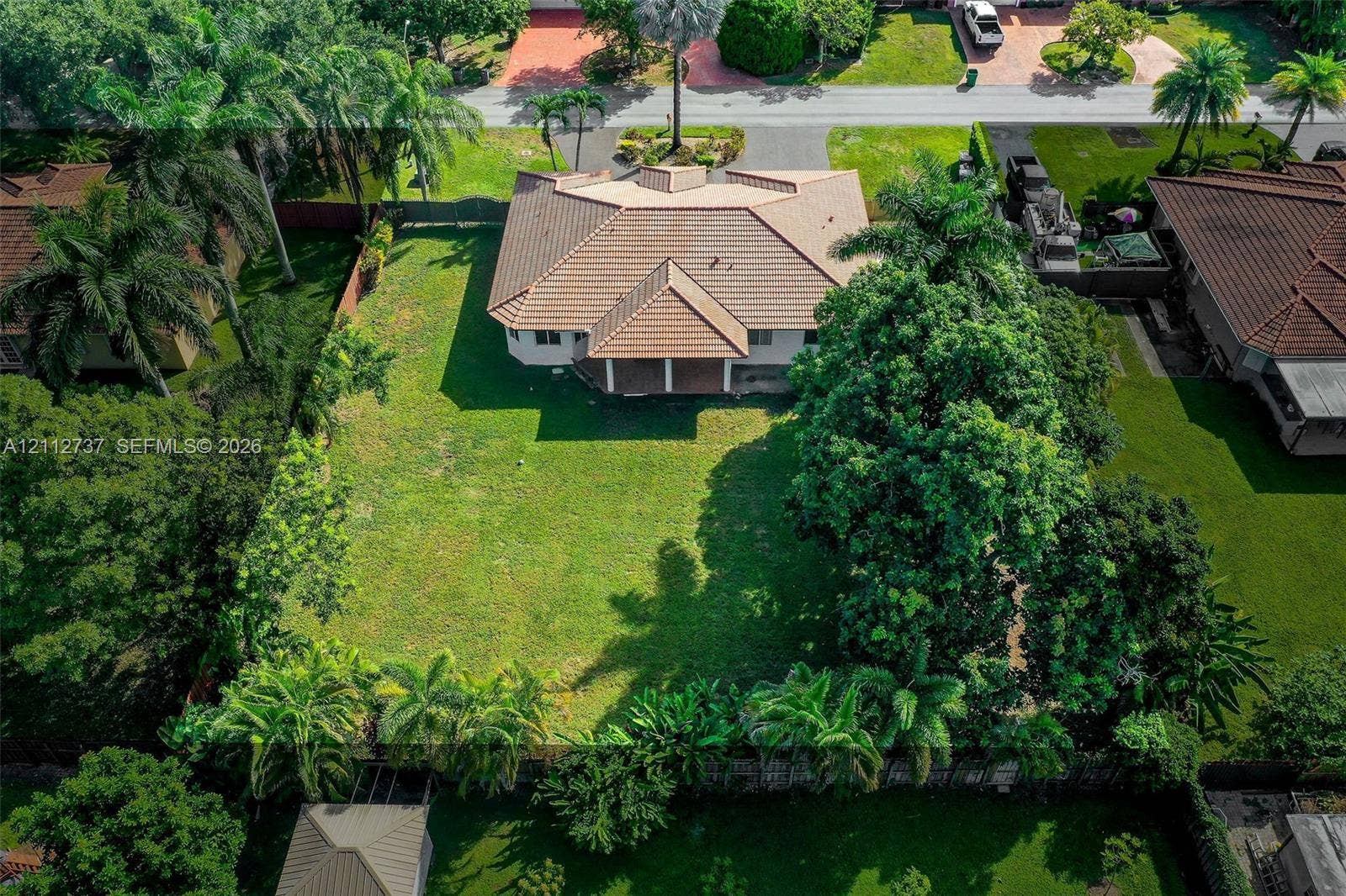 27902 SW 159th Court, Homestead, FL 33031 Expansive lot featuring a multi-gabled tile roof, a rear covered patio, mature landscaping, and an extensive lawn area