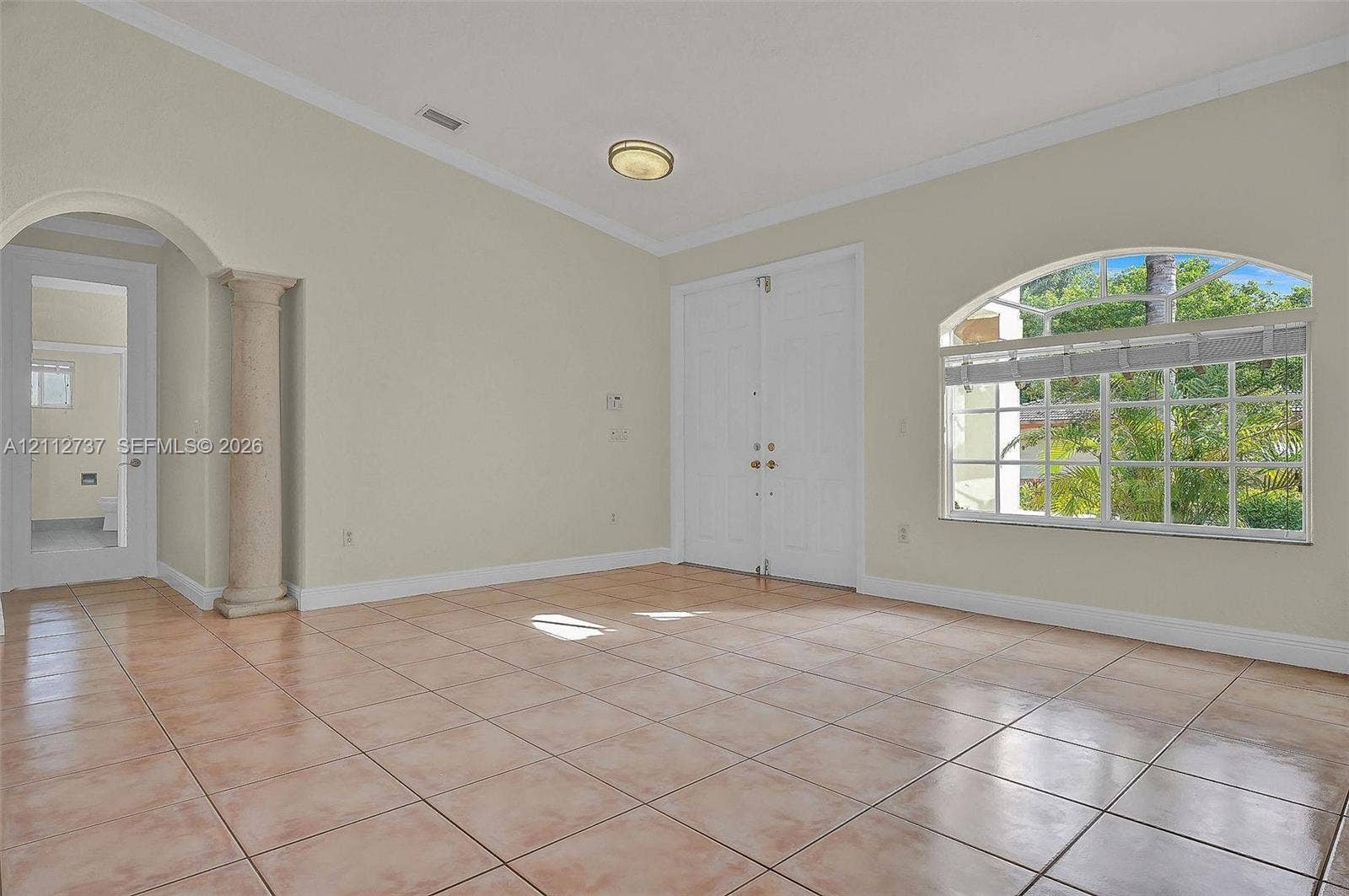 27902 SW 159th Court, Homestead, FL 33031 Vaulted ceiling featuring a central architectural column, ceramic tile flooring, arched window with decorative muntins, and double-door entry